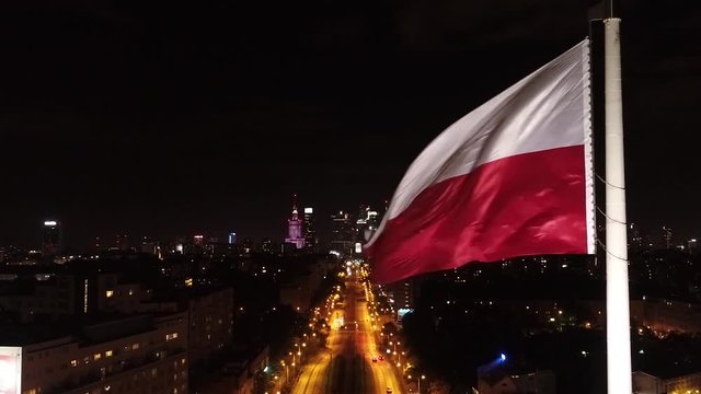 Flaga Polski na tle centrum Warszawy nocą