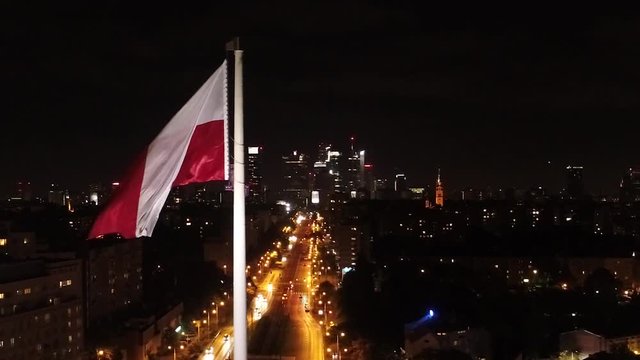 Flaga Polski na tle centrum Warszawy nocą