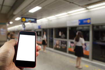 hand holding white blank screen mobile smart phone with people waiting for subway at train station, people, transportation, internet, network connection, technology and social media concept