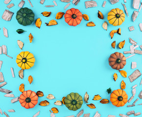 Decorative pumpkins on trendy blue background with fall leaves.