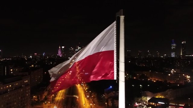 Flaga Polski na tle centrum Warszawy nocą