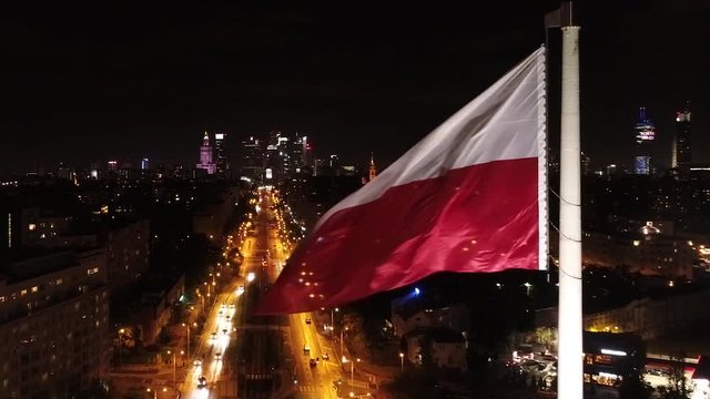 Flaga Polski na tle centrum Warszawy nocą