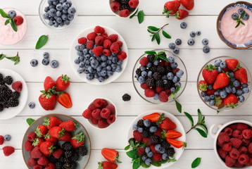 Healthy breakfast with berries and yogurt on white wooden table