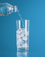 Glasses of water with ice cube on blue background