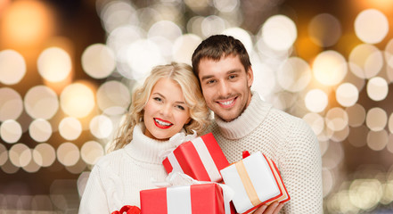 Obraz na płótnie Canvas happy couple in sweaters holding christmas gifts