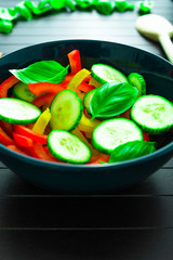 Side view on salad.Salad made of vegetables like green pepper, red pepper, green cucumber and basil. Background as basil leaves.