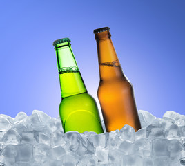 Cold bottle of beer with drops in ice cubes over blue background
