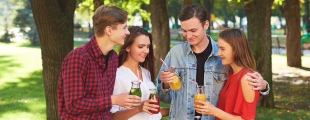 Group of happy young people enjoys detox cocktails and spend time together at summer. Friendship, youth lifestyle, vegetarian diet, fitness food on the go, successful weight loss concept