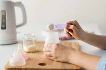 Obraz na płótnie Canvas hands with bottle and scoop making formula milk