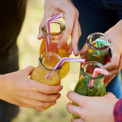 Group of people celebrate with detox juice cocktailss on green nature background. Diet on the go,...