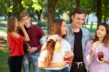 Jealousy and envy in friends relationship. Cheerful young people with detox cocktail having outdoor summer party