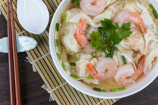 high-angle shot shrimp wonton noodle soup with, on a table set for lunch or dinner.