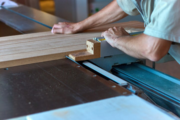 Sawing up of a wooden board on a sliding table saw. Woodworking and carpentry production. Furniture...