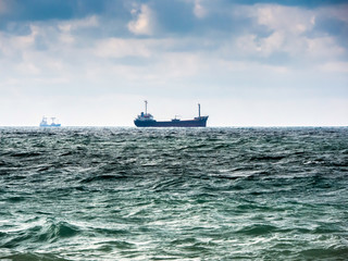cargo ship on the horizon in the sea. cloudy sky