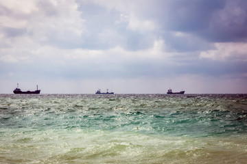 Naklejka premium three cargo ship on the horizon in the sea. cloudy sky
