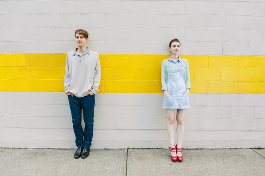 Urban young couple standing against a wall