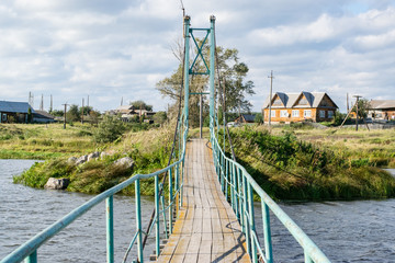 Russian rural landscape with a bridge over river