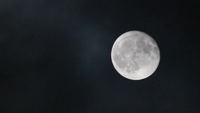 full moon with moving clouds in the night sky

