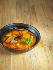 Mushroom soup in brown bowl on wooden table.