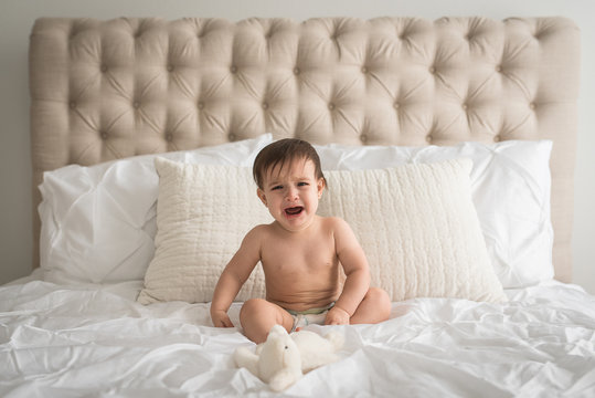 A Baby Girl On A Bed Cries