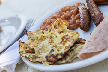 Englisches Frühstück mit Baked Beans, Würstchen, Wurstaufschnitt und Omelett im Hotel