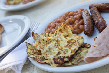 Englisches Frühstück mit Baked Beans, Würstchen, Wurstaufschnitt und Omelett