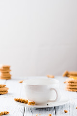Empty cup ready for hot drink with cookies on white rustic wooden table