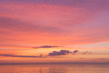 Fototapeta na wymiar Serene tender pink sunset on the ocean with small clouds. Background for calmness