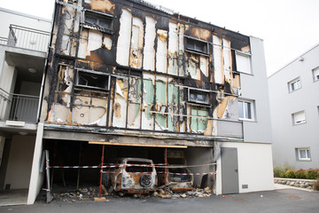 Cars after a fire with burnt building