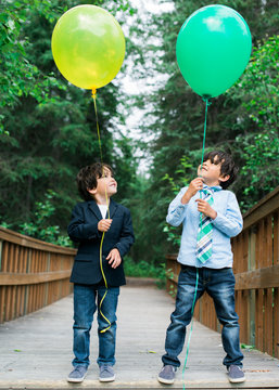 two young boys looking up at their helium balloons