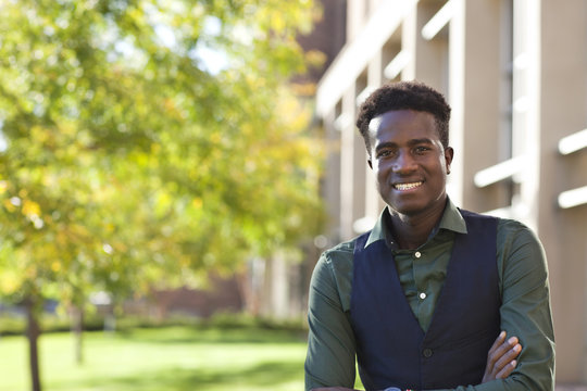 Handsome young black student man smiles standing on colege campus