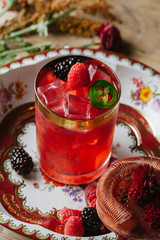 Pink color cocktail on rustic surface garnished with berries and fall flowers