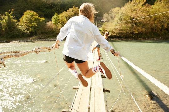 Rear view of woman jumping on bridge