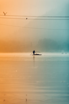A silhouetted man makes his way across Dal Lake at sunrise