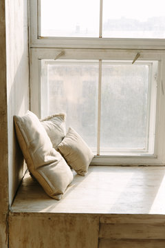 Photo of three beige pillow on window sill