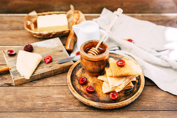 Fresh homemade crepes with honey and berries over rustic background
