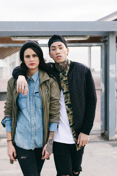 Portrait of a young alternative couple standing outside.