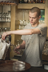 Pouring fresh beer. Close-up of young bartender pouring beer while standing at the bar counter