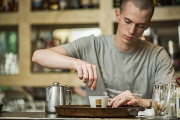 Barista bartender stirring coffee in a small espresso cup in a coffee shop
