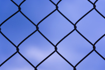 Fototapeta premium Fence texture. Clear blue sky in the background of mesh.