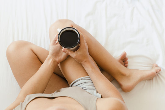 Woman in the bed is drinking a coffee