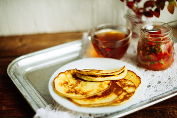 Home-made breakfast or brunch: american style pancakes served with berries and sugar powder on vintage metal tray with a cup of black tea