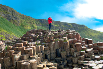 A man in a Landscape of Giant's Causeway trail with a blue sky in summer, Co. Antrim, tourism in Northern Ireland in United Kingdom. UNESCO heritage.