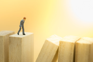 Business and Risk management concept. Businessman miniature figure walking on collapse wooden blocks toy.