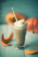 Pumpkin smoothie, spice latte with whipped cream on top on a turquoise wooden background. copy space