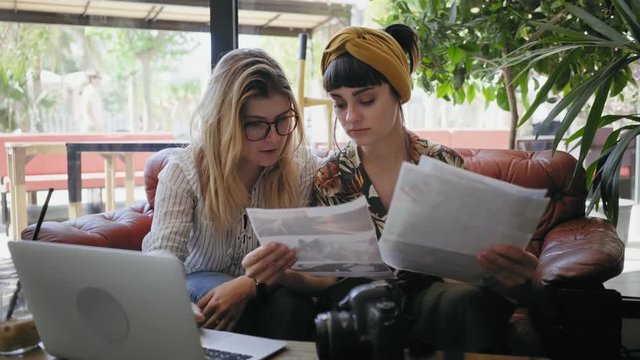 Two girls have non official meeting in cafe to discuss their project. Planning shooting for stock photography or advertisement company. Art director meets producer.