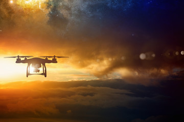 Silhouette of flying drone in glowing red sunset sky