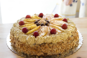 delicious homemade cake with coffee cream decorated by red grape and pears on silver plate  on wood table