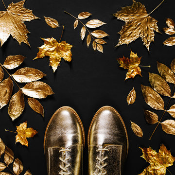 Autumn composition. Pattern made of autumn golden  leaves and stylish shoes on  black background. Flat lay, top view