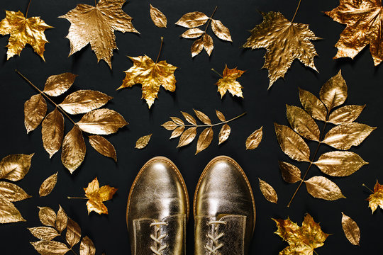 Autumn composition. Pattern made of autumn golden  leaves and stylish shoes on  black background. Flat lay, top view